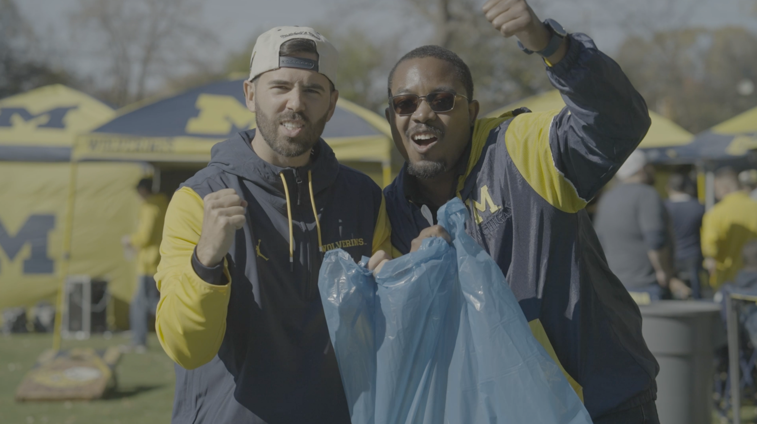 University of Michigan football fans hold a blue recycling bag during the Recycle Bowl, encouraging PET bottle recycling and game-day sustainability.